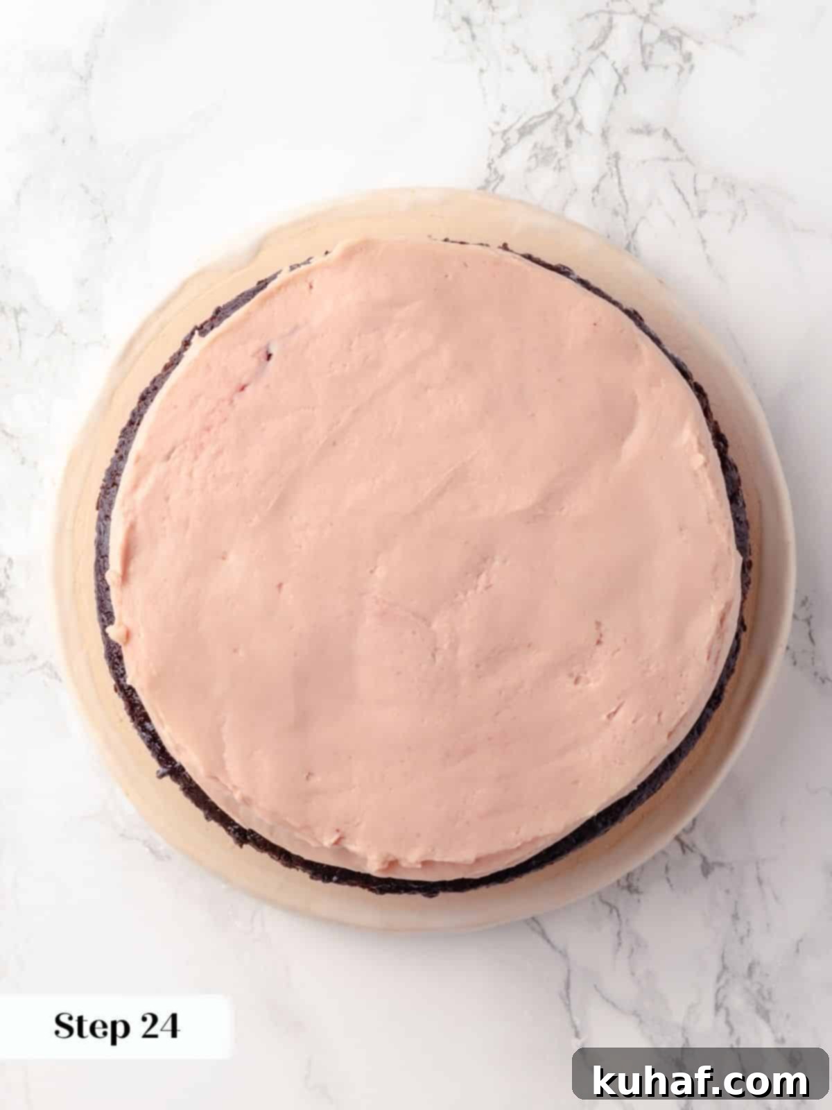 A smooth layer of vibrant raspberry buttercream carefully spread over the raspberry jam, creating a level surface on the cake layer.