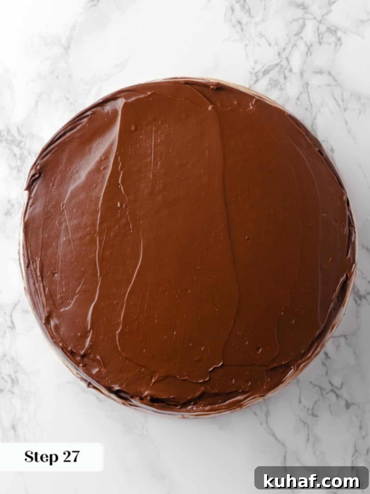 Rich chocolate frosting being artfully smoothed onto the top layer of the chocolate raspberry cake with a spatula, creating a perfect finish.