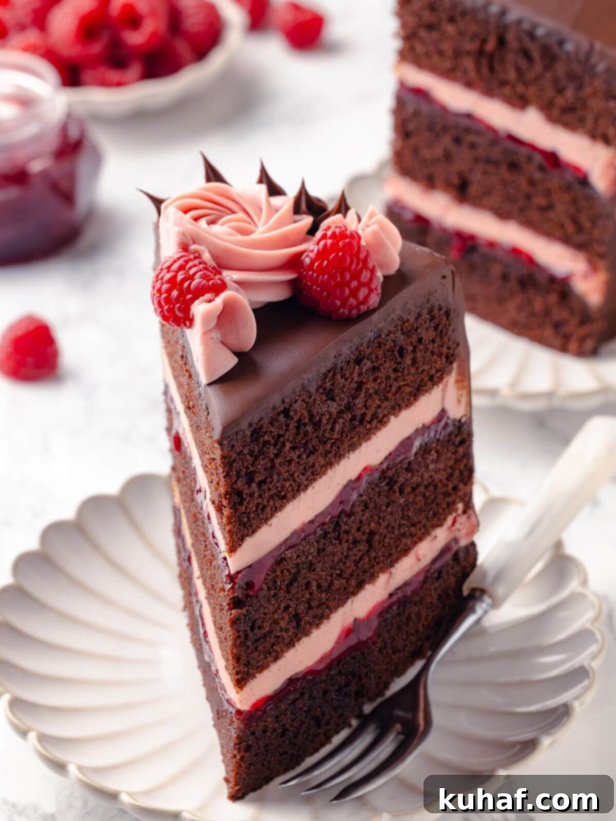 A perfectly portioned slice of chocolate raspberry cake served on a elegant white plate, garnished with fresh raspberries for a touch of color.