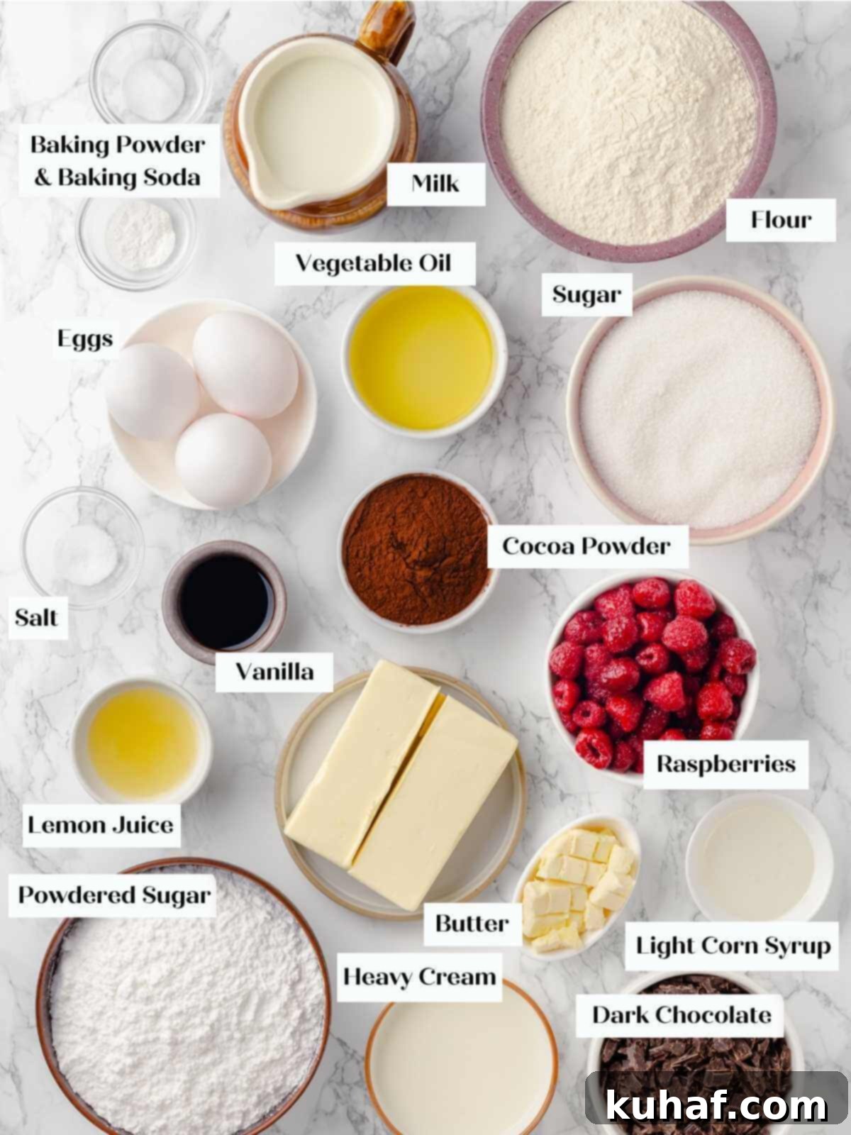 A flat lay of all the chocolate raspberry cake ingredients arranged artfully on a white marble surface, ready for baking.