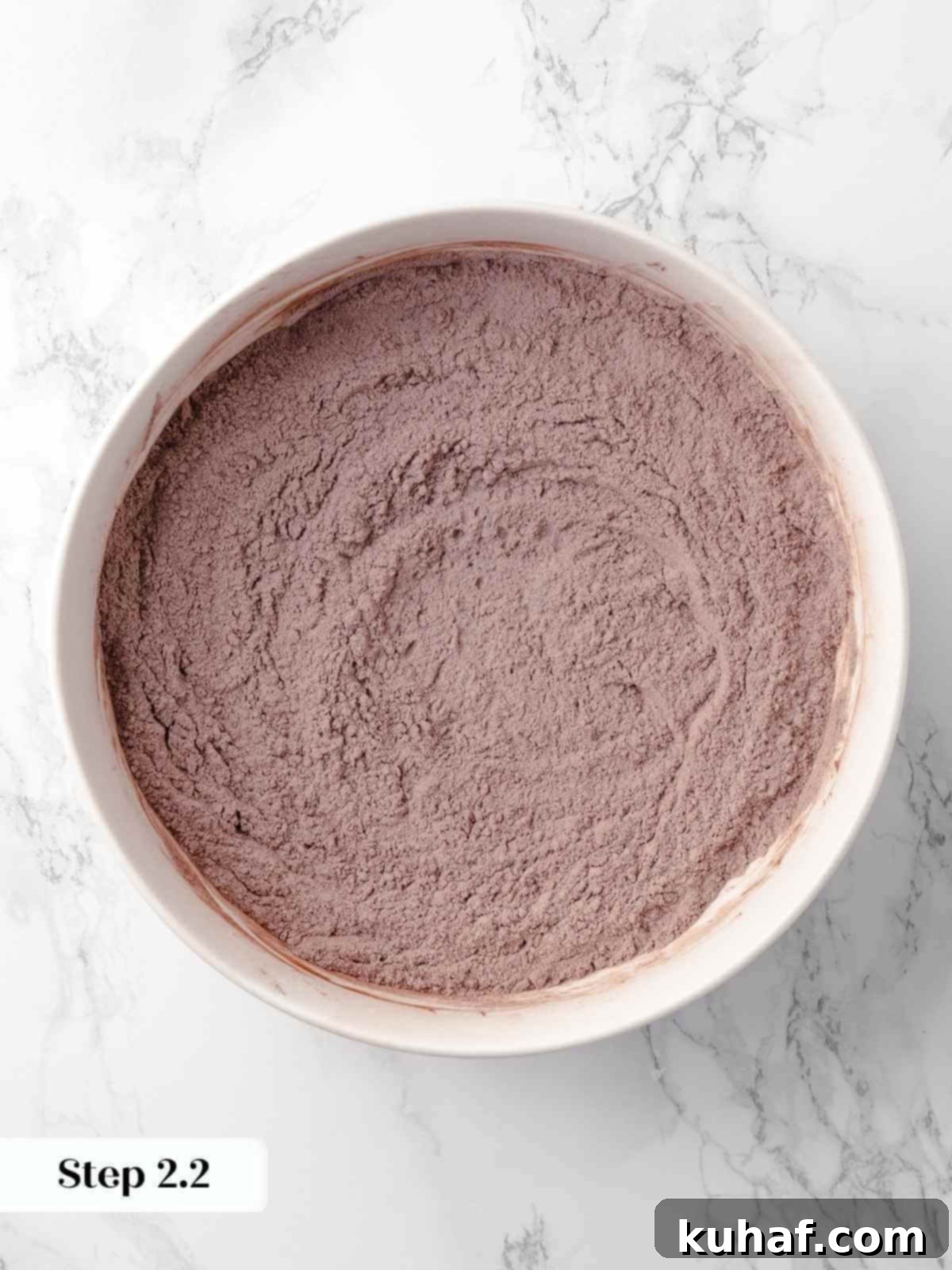 Dry ingredients for the chocolate cake, including cocoa powder and flour, mixed together in a bowl, showcasing their uniform blend.