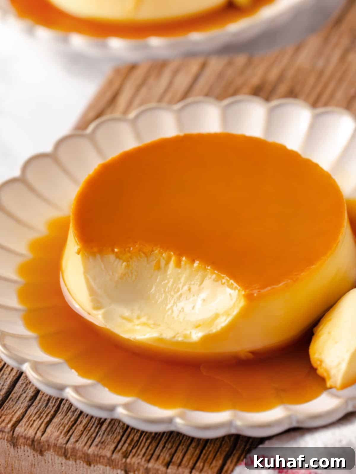 A creme caramel dessert with a bite taken out, revealing its creamy, smooth texture and glistening caramel.