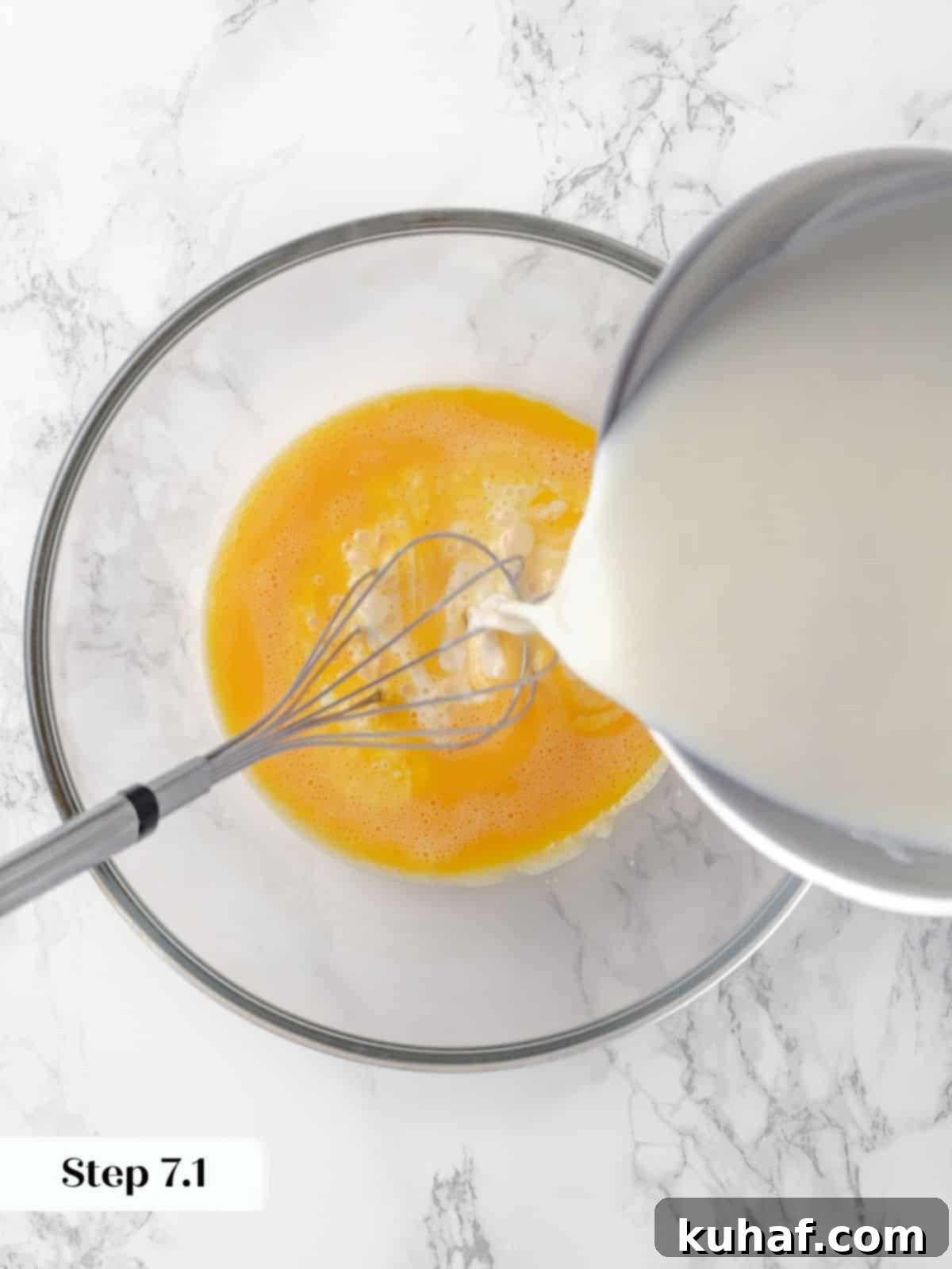 Warm milk mixture being slowly poured into whisked eggs, a crucial tempering step to create a smooth custard for crème caramel.
