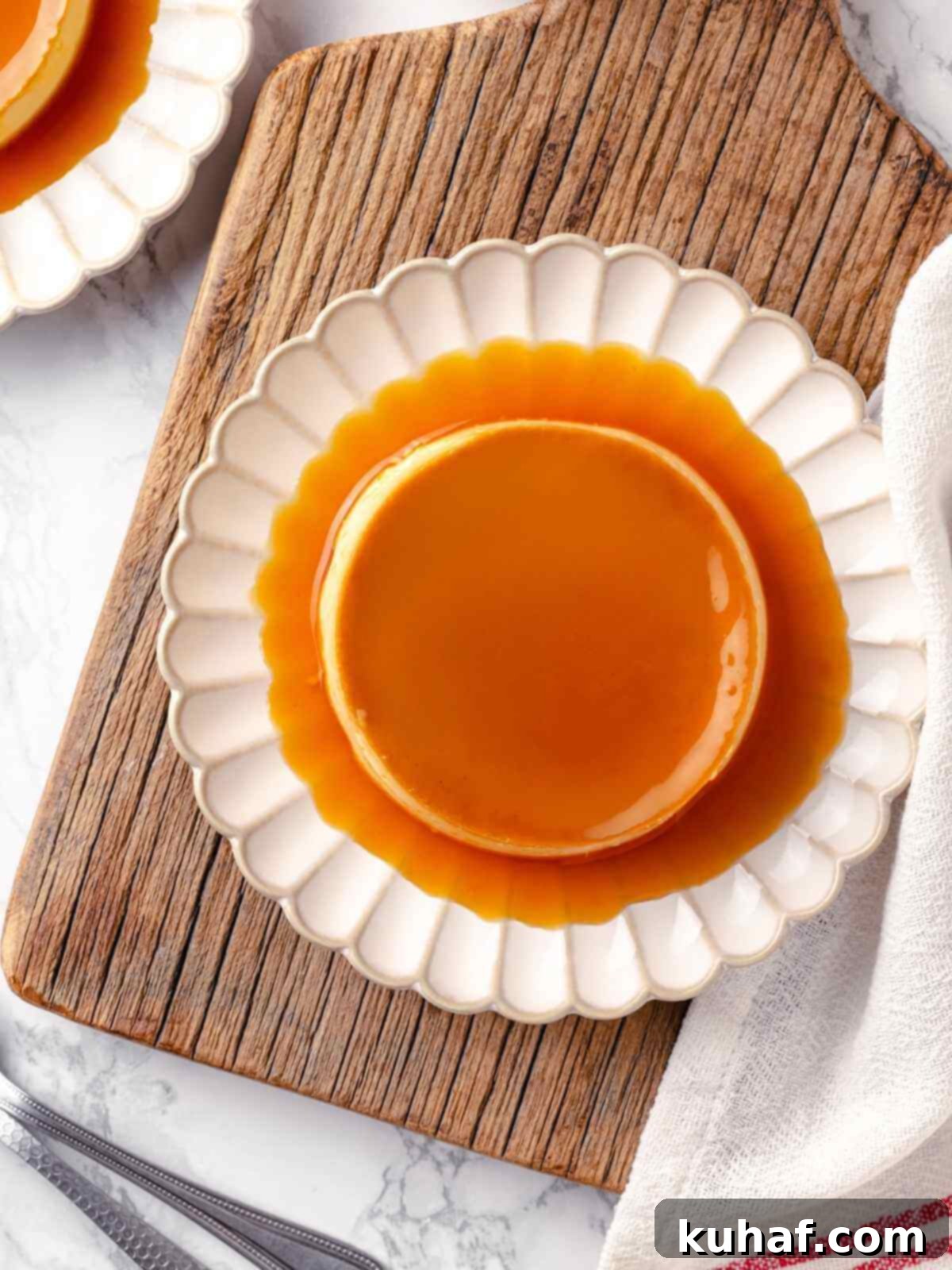 A perfectly unmolded crème caramel, shimmering with its amber caramel sauce, served elegantly on a white plate.