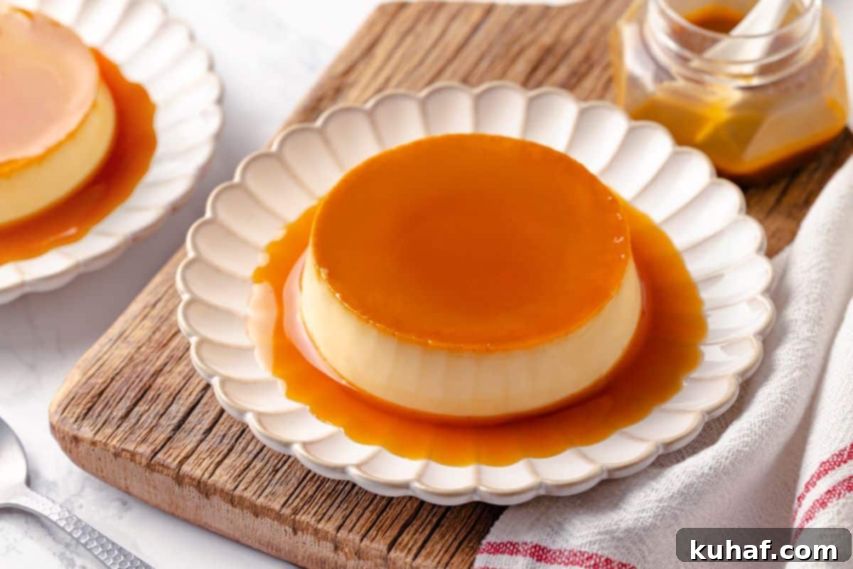 A beautifully plated creme caramel dessert, perfectly unmolded, with its glossy caramel sauce pooling at the base on a white plate.
