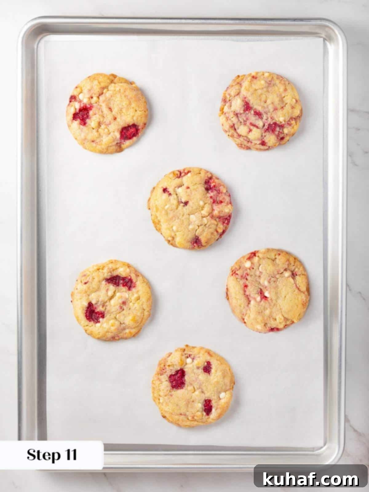 Luscious White Chocolate Raspberry Cookies 15 A baking tray filled with freshly baked white chocolate raspberry cookies, golden-brown and cooling slightly.