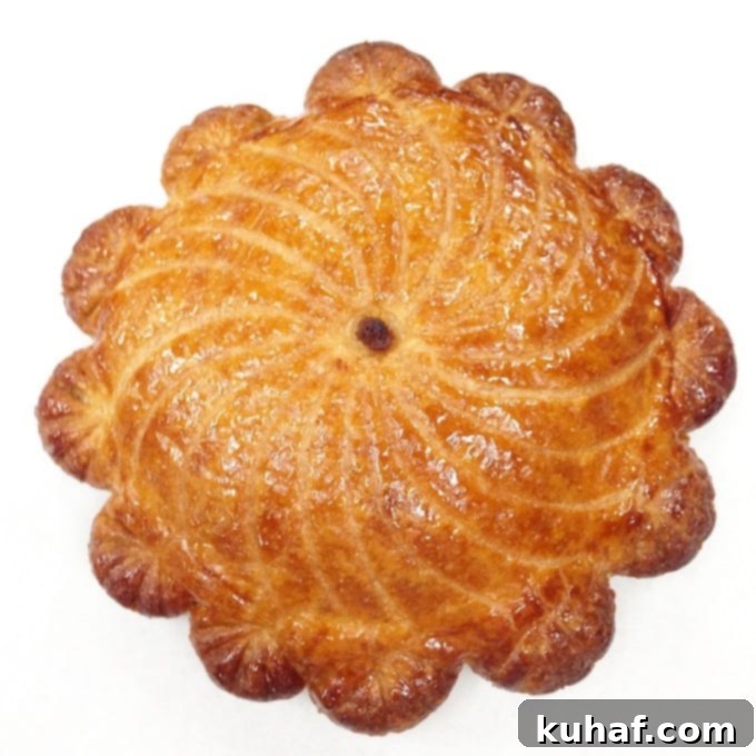 A stunning Gâteau Pithivier, a classic French puff pastry cake filled with frangipane, intricately scored and baked.
