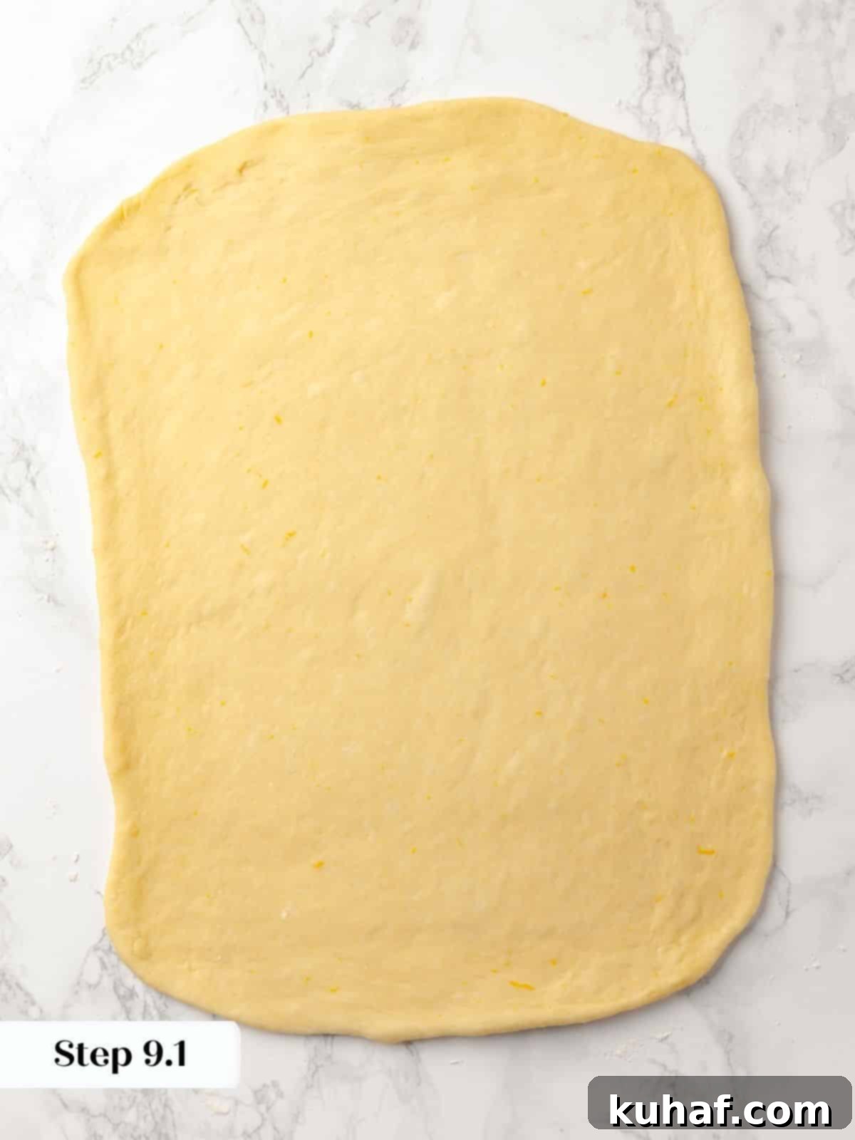 Sticky bun dough rolled into a large rectangle on a floured surface.