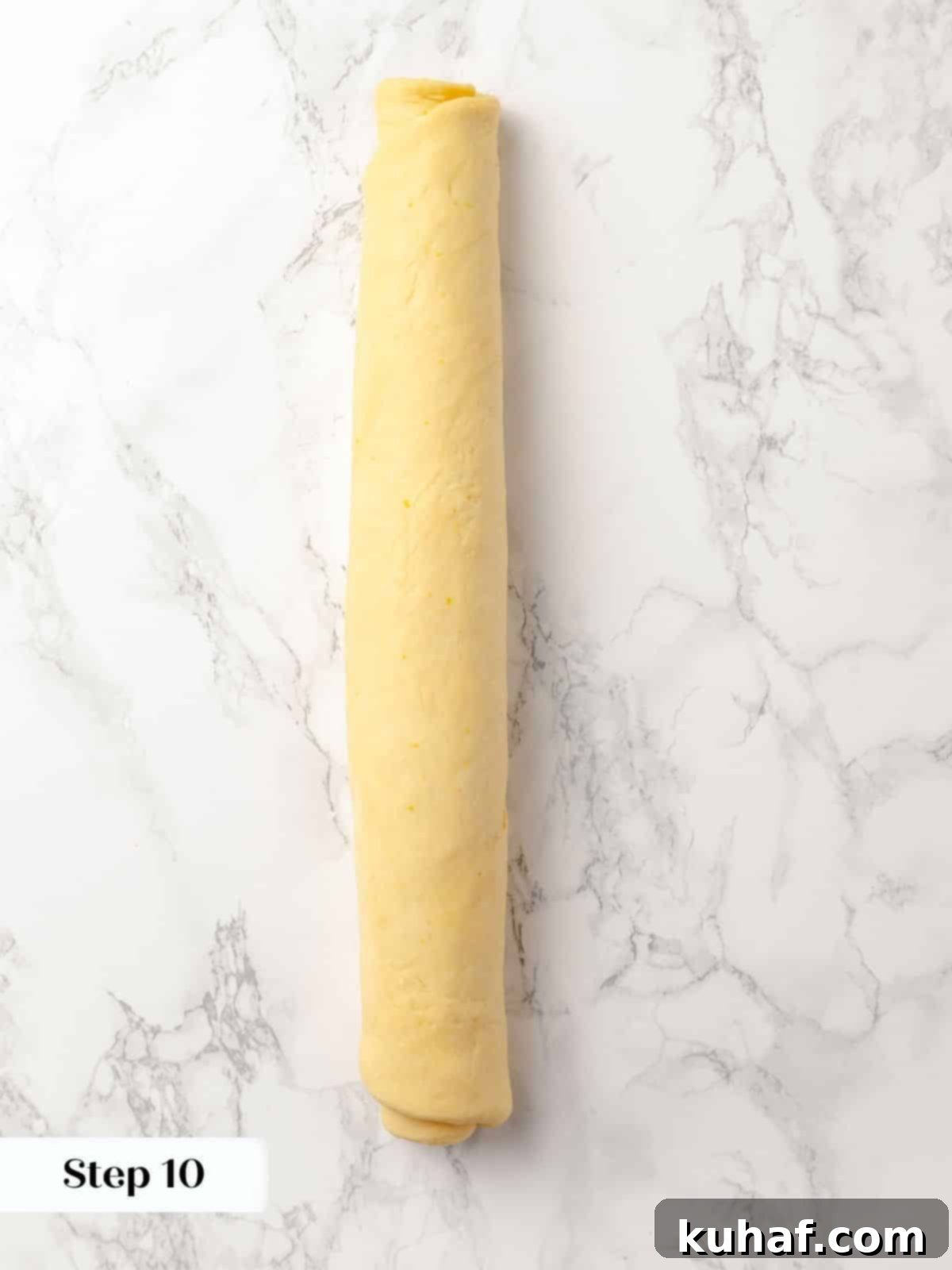 Cinnamon-filled sticky bun dough rolled into a tight log before cutting.