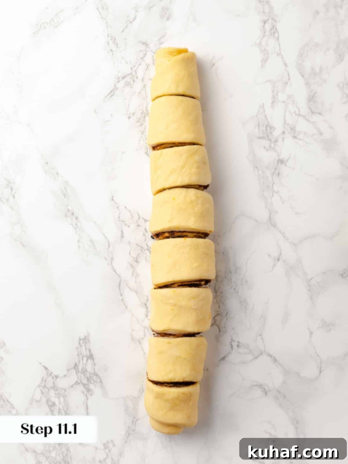 A rolled log of sticky bun dough sliced into even pieces.