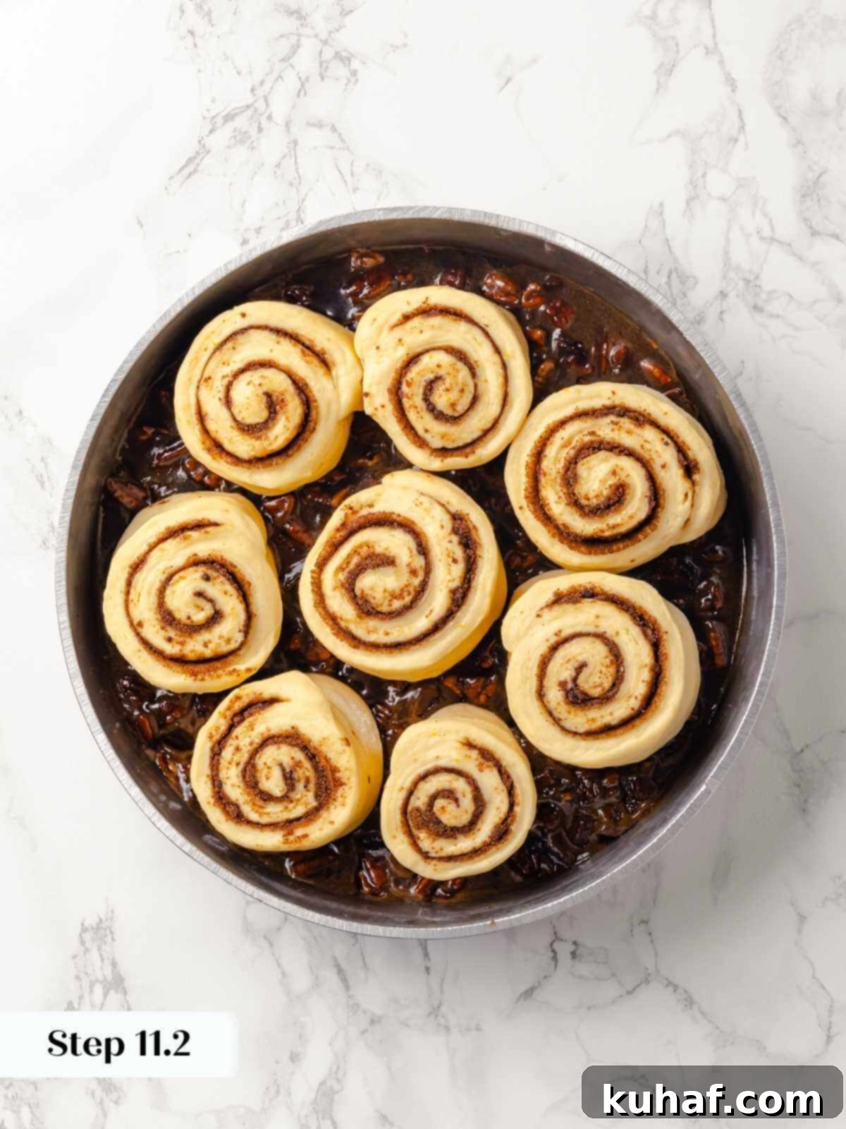 Cinnamon-swirled dough pieces placed in a round pan for baking.