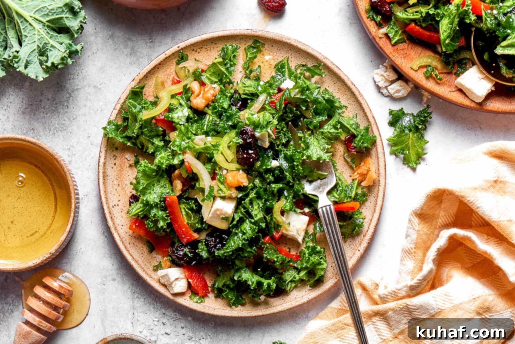 A beautifully presented plate of chopped kale salad, garnished with cranberries and walnuts, set next to a crisp cloth napkin.