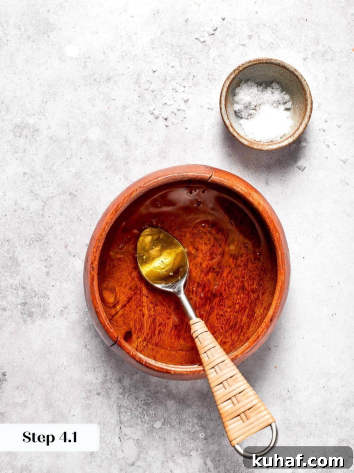 A close-up shot of apple cider vinaigrette being generously drizzled over the prepared chopped kale, onions, and peppers in a large mixing bowl.