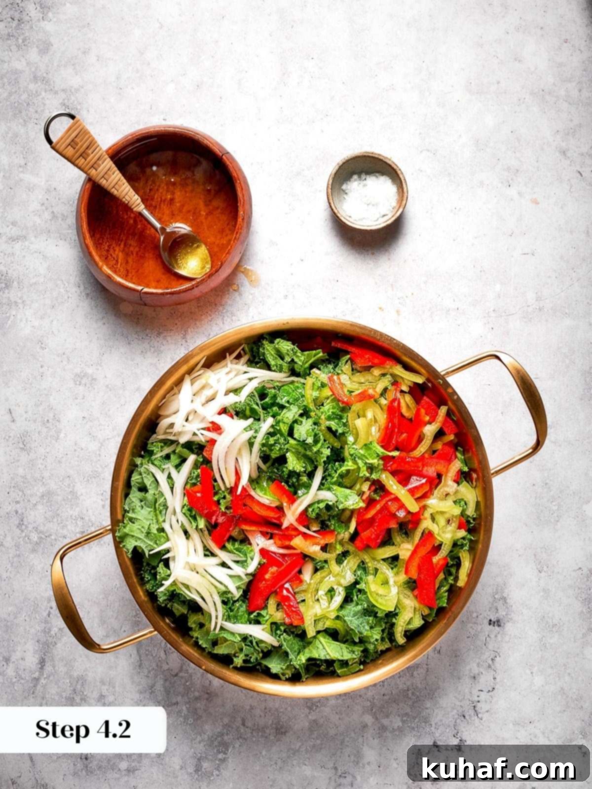 The apple cider vinaigrette beautifully drizzled over a mix of fresh kale and colorful bell peppers in a large mixing bowl, ready for massaging.