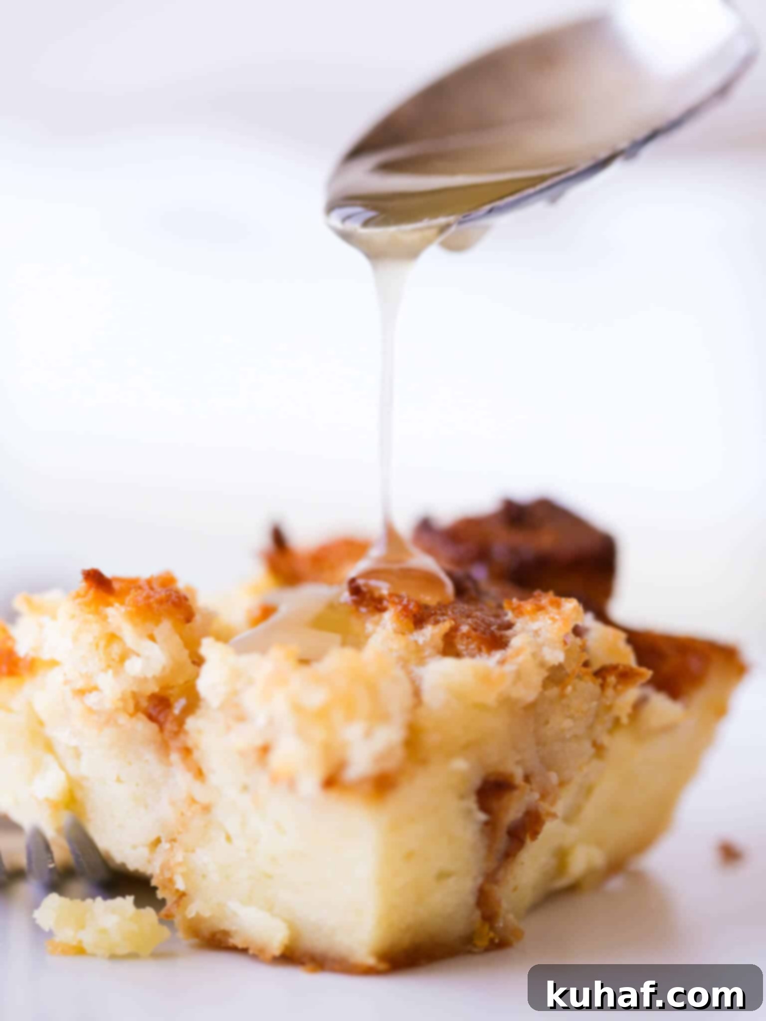 A glistening slice of Lemon Raspberry Bread Pudding with a lemon glaze drizzle