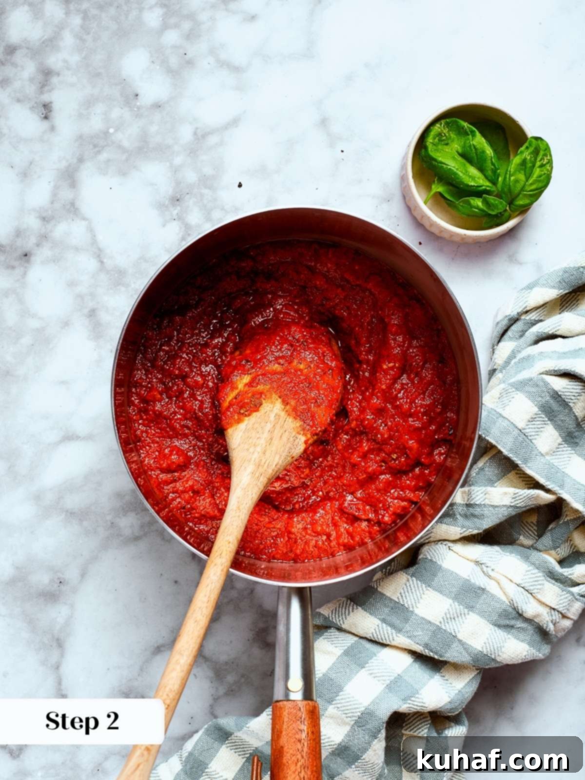 Perfect Homemade Pizza Sauce 6 A spoon stirring thickened tomato sauce in a saucepan.