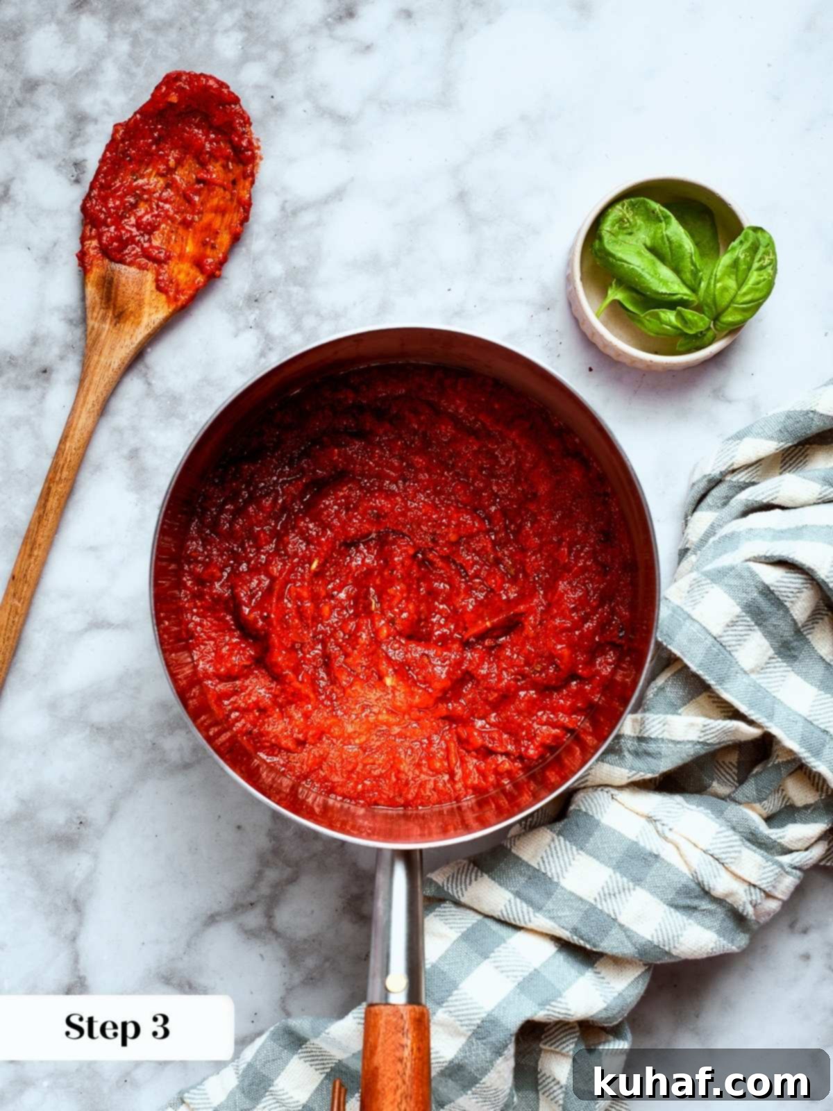 Perfect Homemade Pizza Sauce 7 A small spoonful of sauce next to a saucepan for tasting.