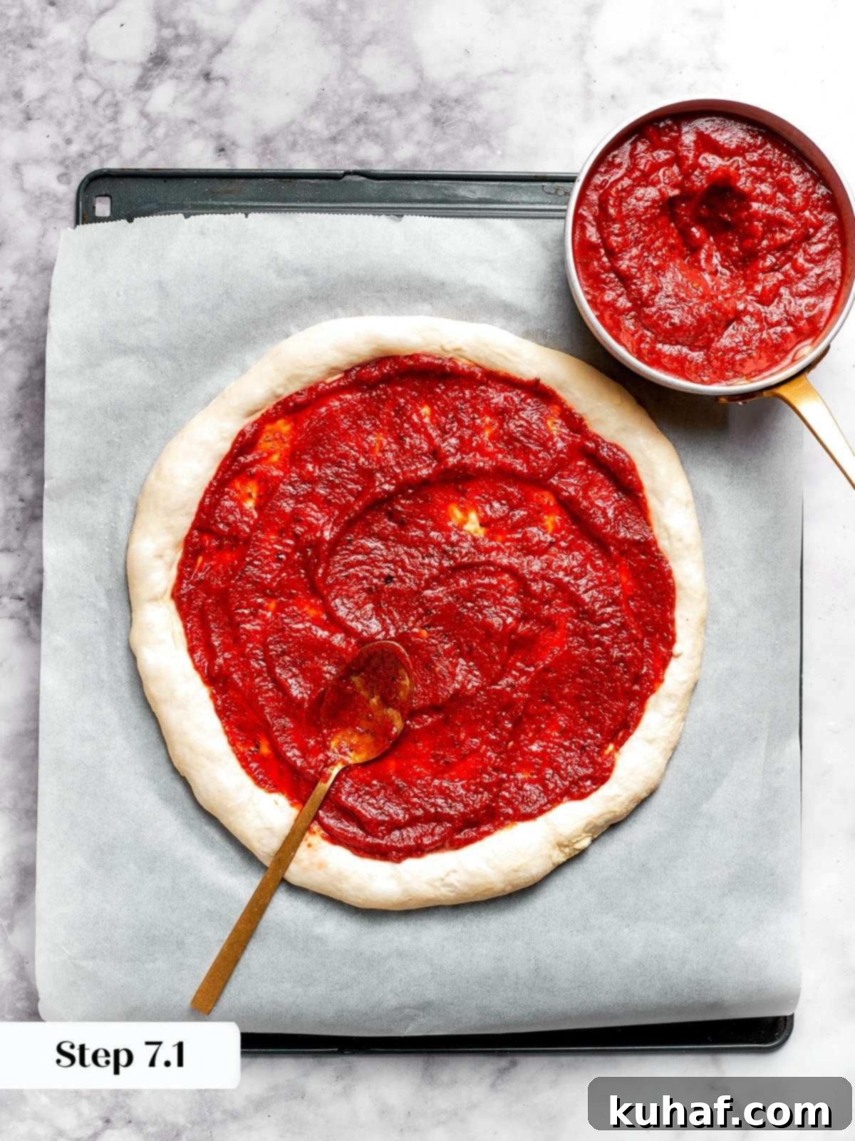 Tomato pizza sauce being spread onto round pizza dough.
