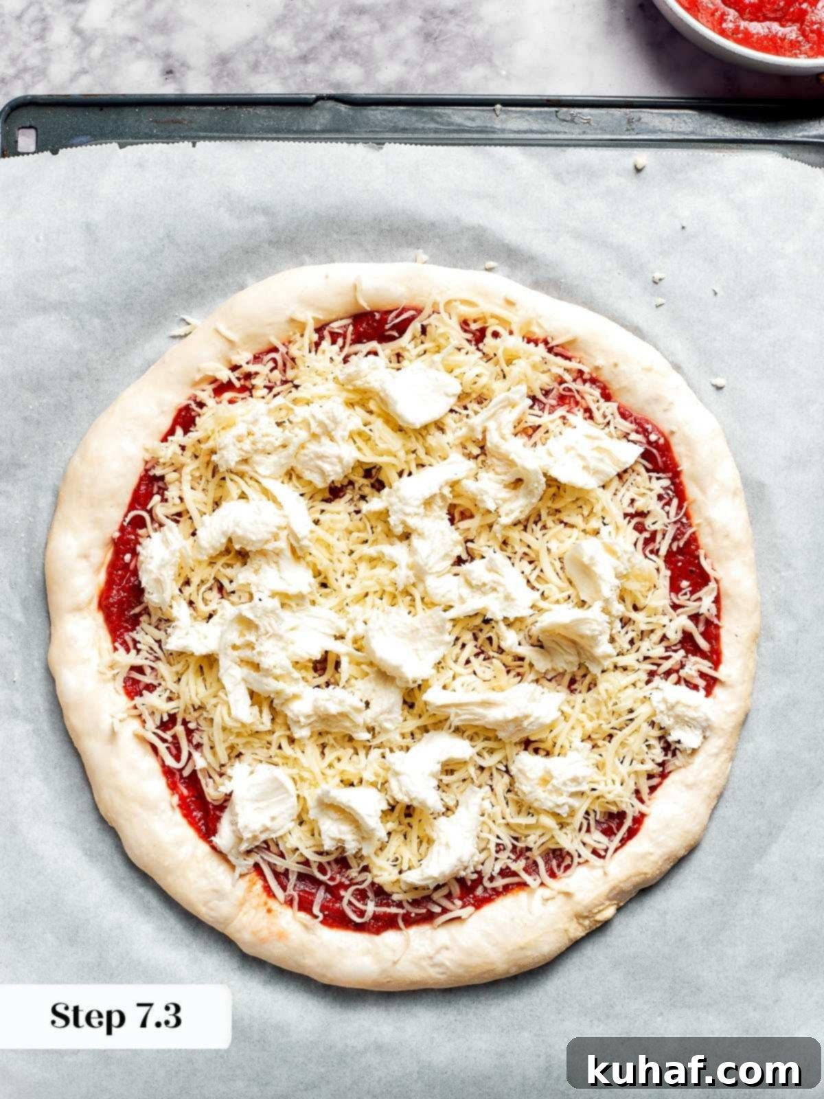Topping the pizza dough with fresh mozzarella before baking.