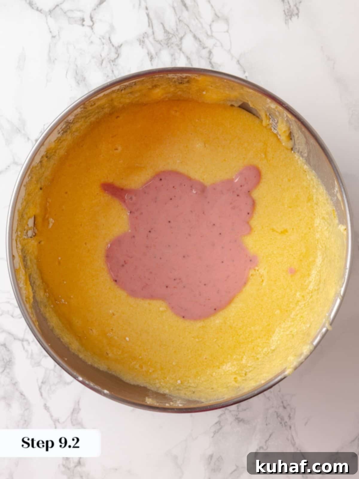Strawberry-swirled sour cream mixture being added to the cake batter during the mixing process.