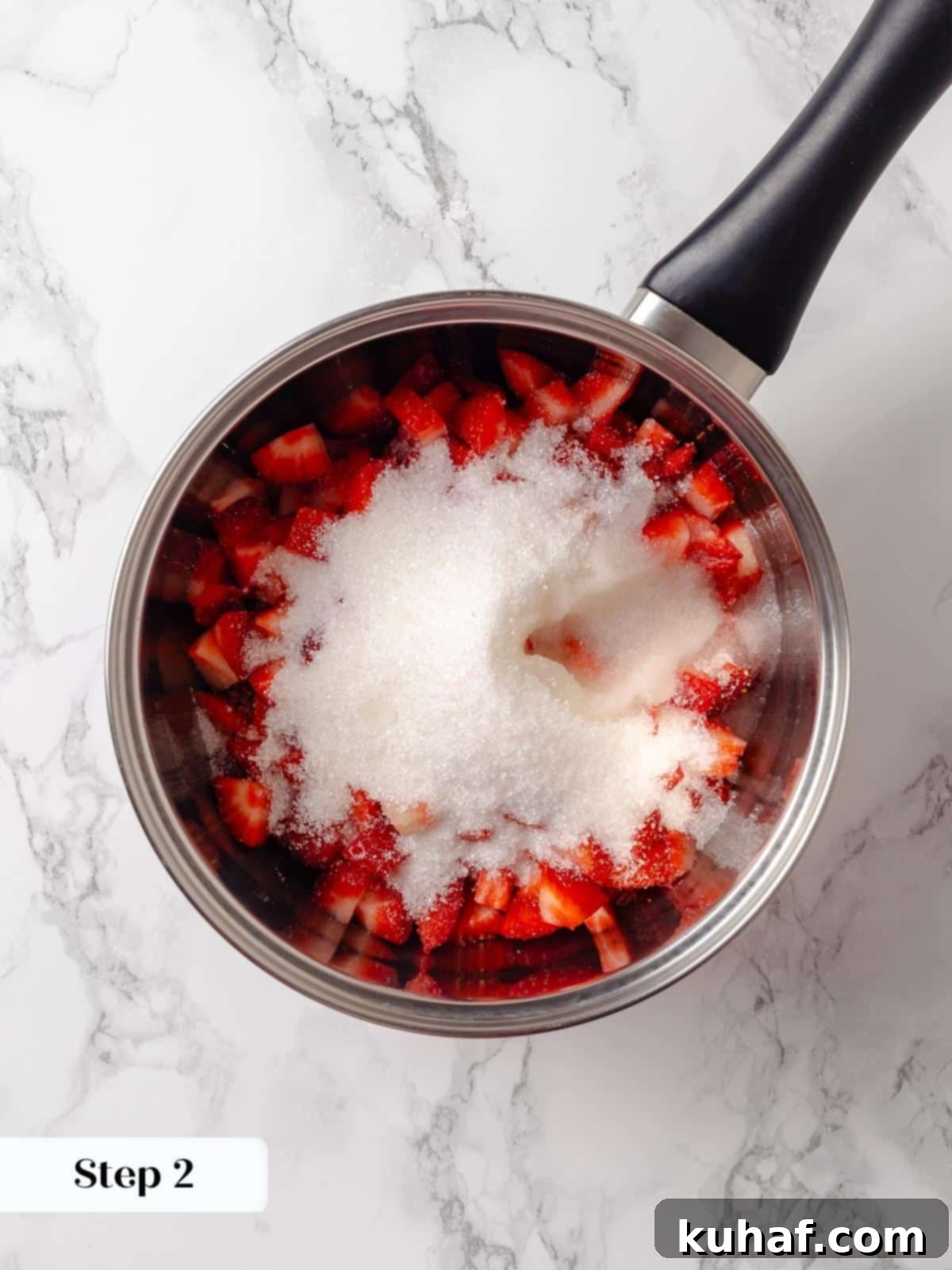 Fresh strawberries, granulated sugar, and lemon juice combined in a pot, ready to be cooked into jam.
