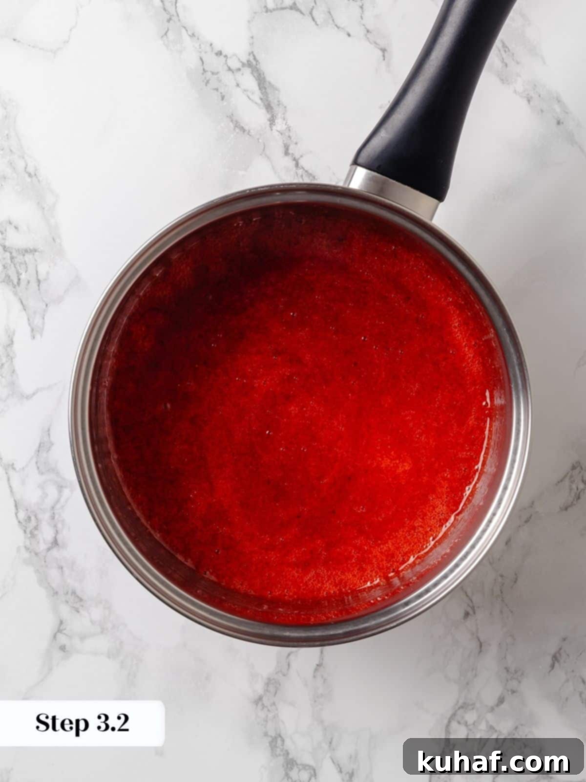 Strawberry jam finished cooking, thickened and glossy in the saucepan, indicating readiness.