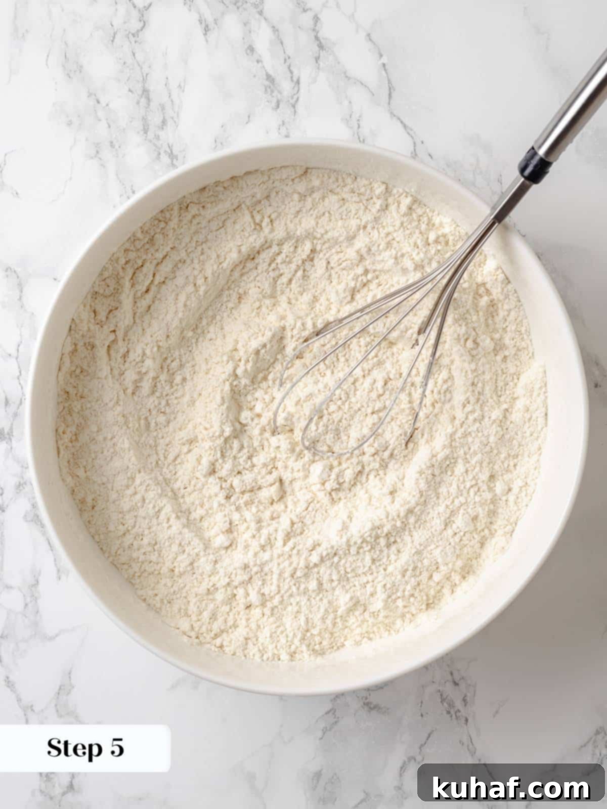 Whisking all-purpose flour, kosher salt, and baking soda together in a large bowl for even mixing of dry ingredients.