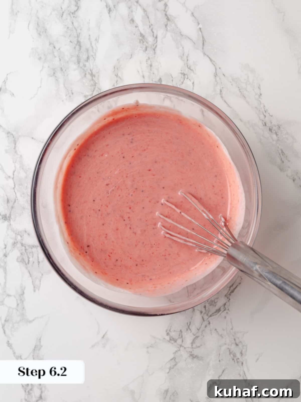 Sour cream blended smoothly with strawberry jam, forming a creamy pink mixture ready for the cake batter.