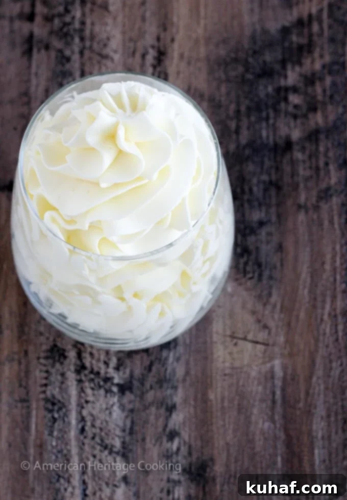 Italian meringue buttercream elegantly piped into a clear glass, showing graceful swirls and a perfect, stable texture.