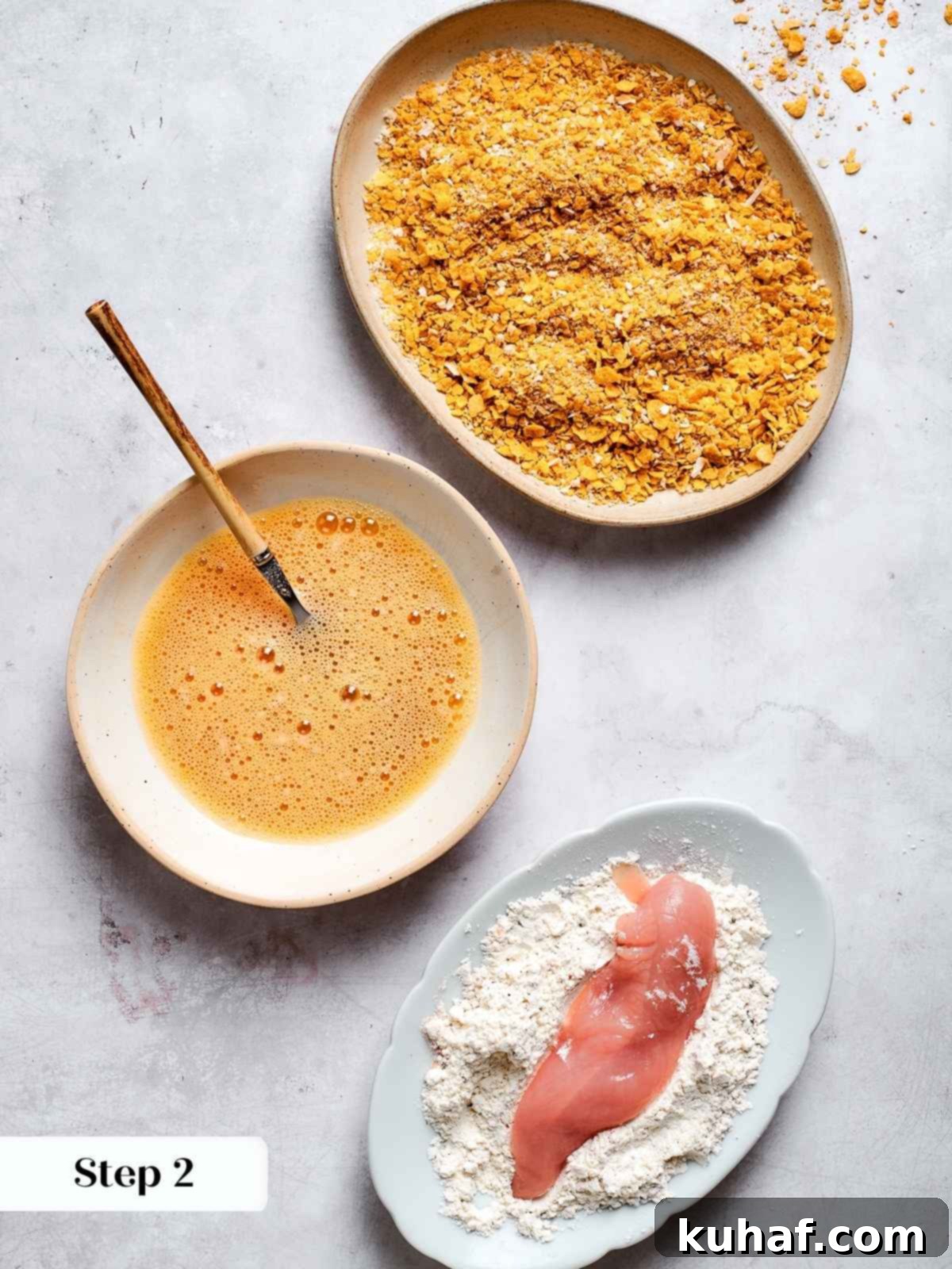 Chicken tenders being coated in a seasoned flour mixture on a plate, the initial step in the breading process.