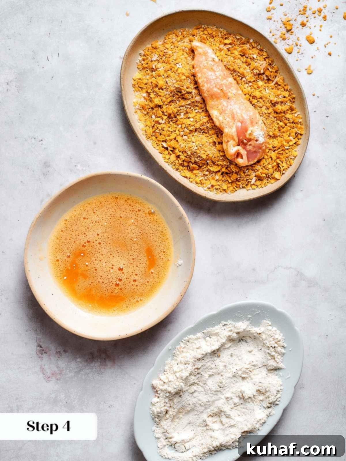 Chicken tenders being pressed into the Chex and breadcrumb coating mixture, ensuring full coverage before air frying.