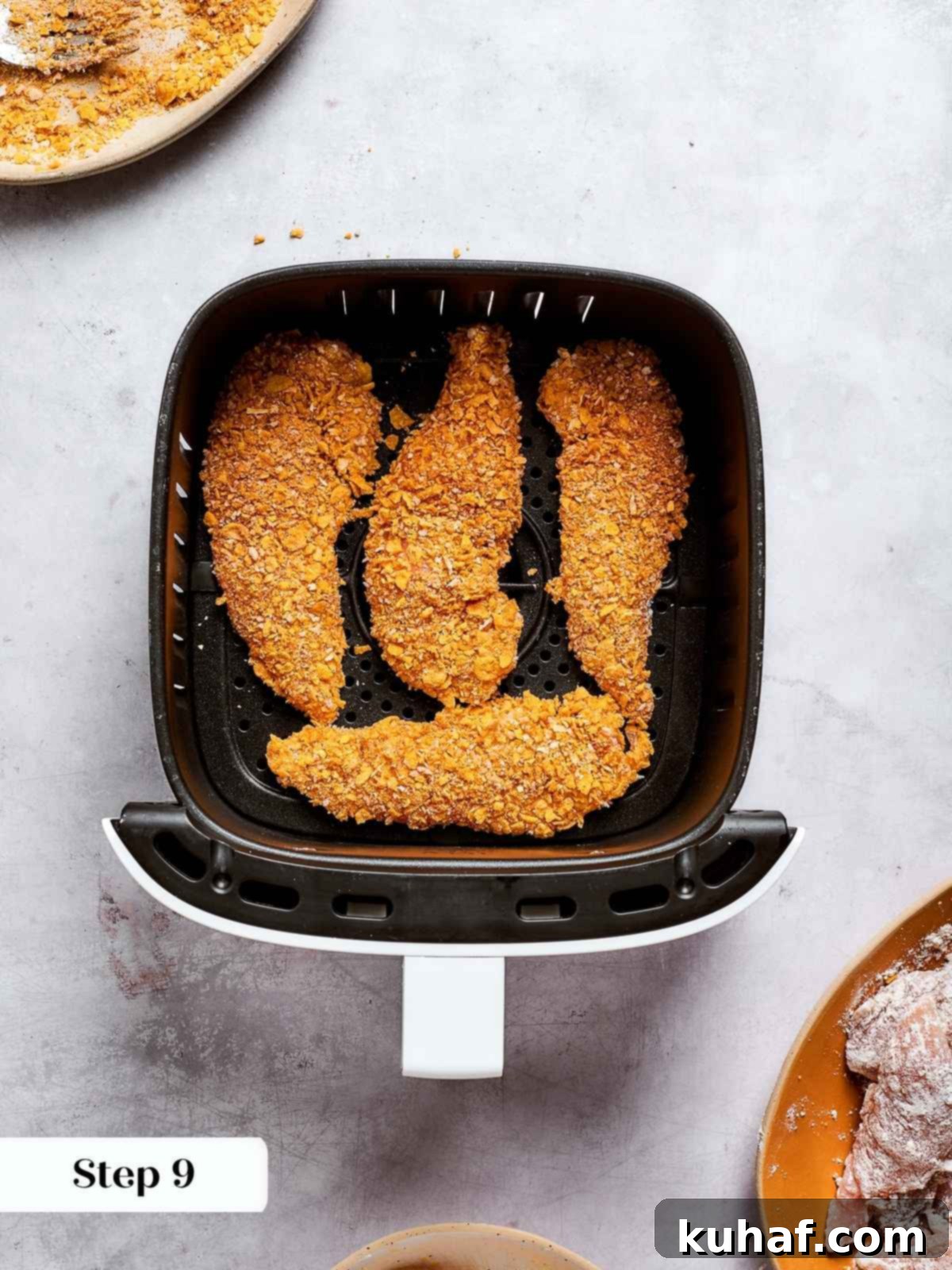 Perfectly coated chicken tenders lined up neatly in an air fryer basket, ready to be cooked to golden crispness.