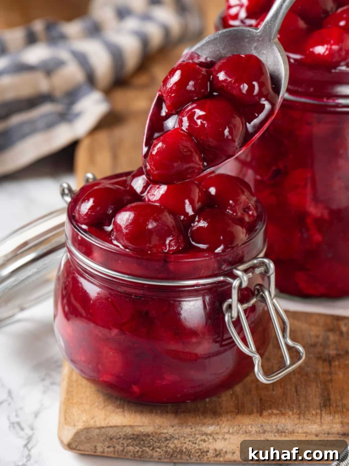 Cherry pie filling being spooned from a small jar, showing its texture and shine.