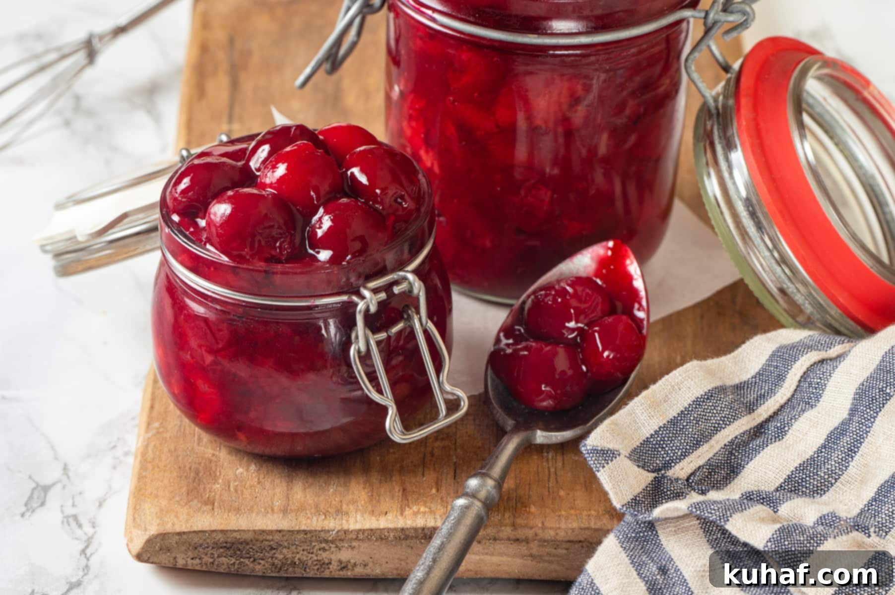 Thick, glossy cherry pie filling clings to spoon, showing texture and visible chunks of fruit.