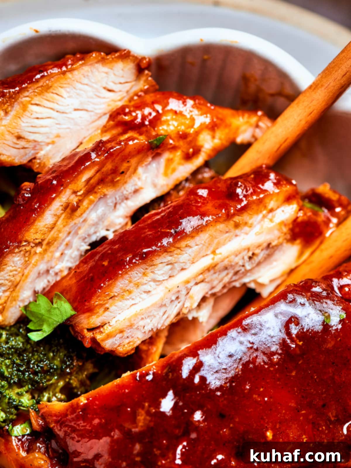 Chicken breasts and thighs sliced after cooking, covered in red sauce and plated, garnished with sesame seeds and green onions.