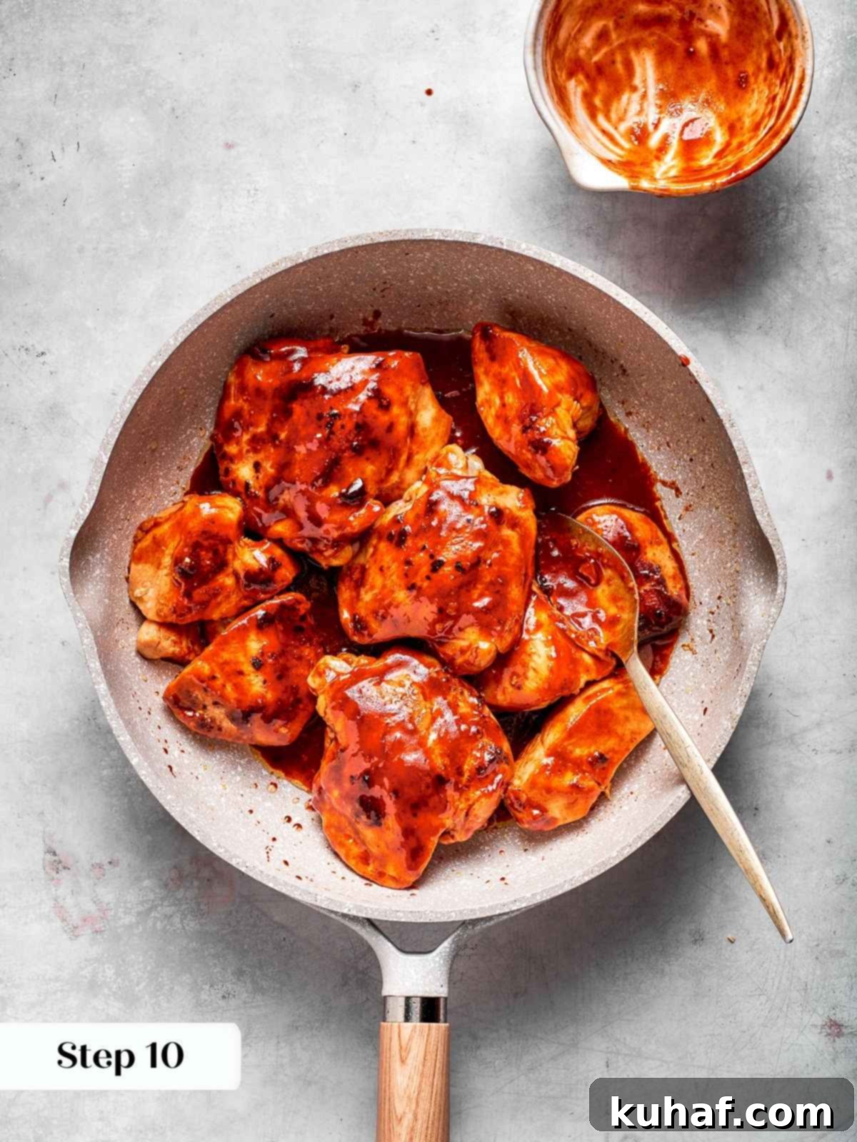 Cooked chicken coated in a luscious, thick red gochujang sauce after simmering in a pan, showcasing the rich, sticky texture.