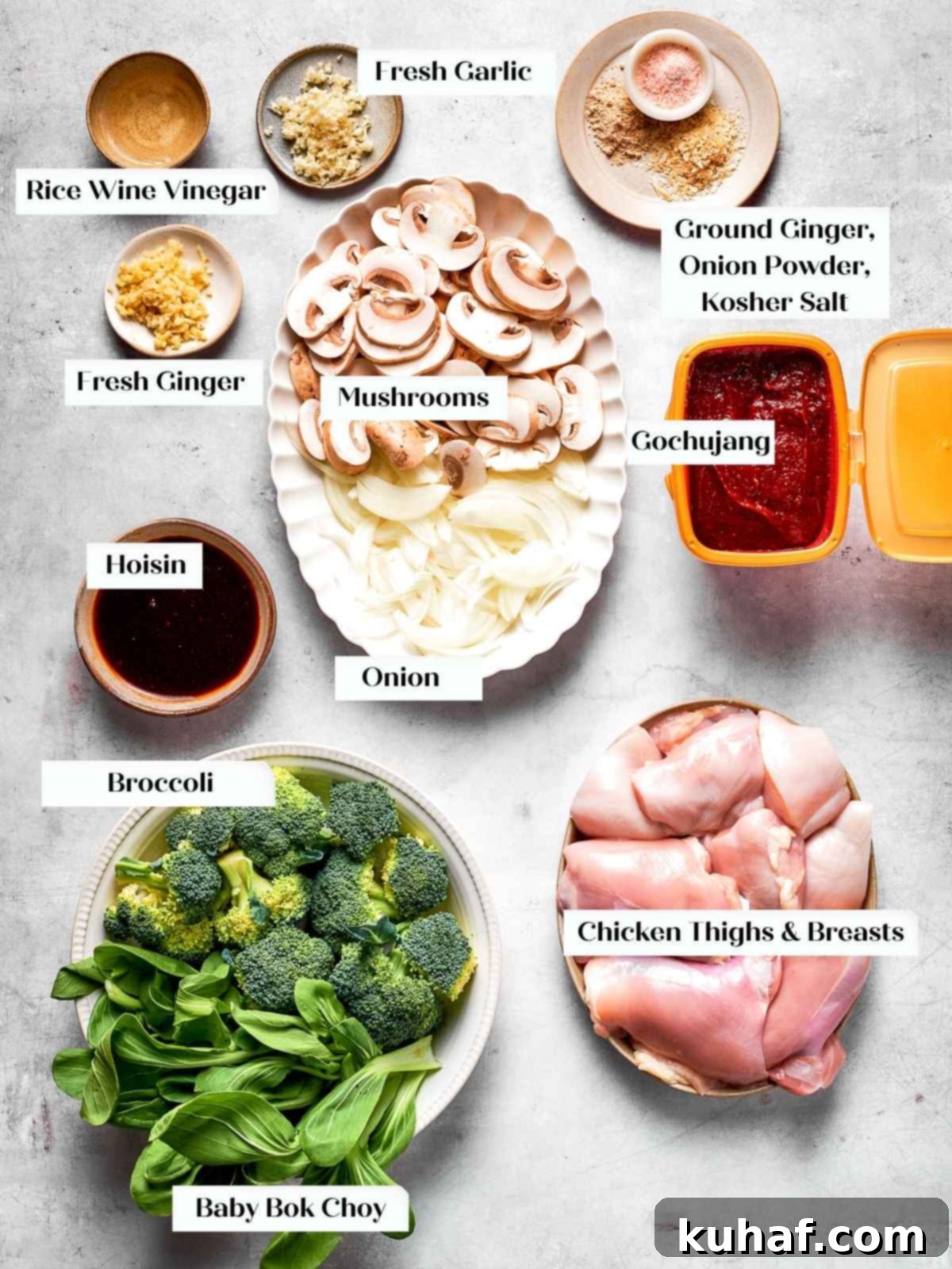 Raw ingredients including chicken, bok choy, mushrooms, garlic, and a jar of gochujang laid out on a kitchen counter, ready for preparation.