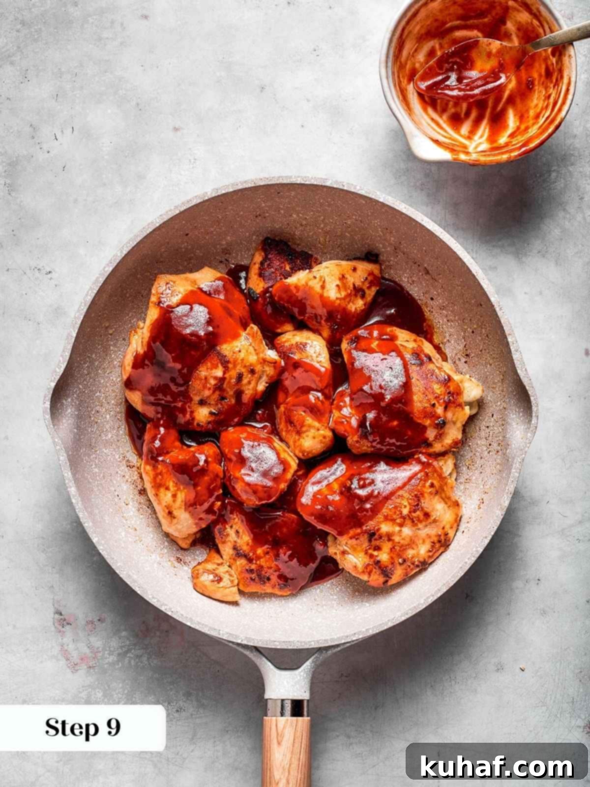 Seared chicken pieces being coated with the freshly stirred, vibrant red gochujang sauce in the skillet, ready to simmer to sticky perfection.