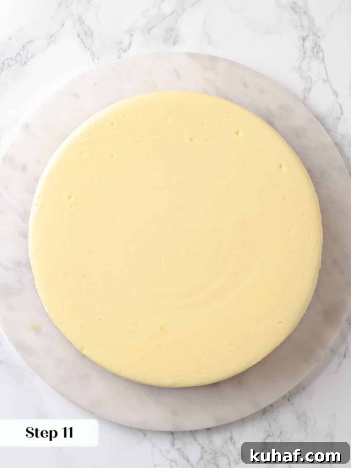Fully chilled cheesecake resting on marble surface before the topping is added.