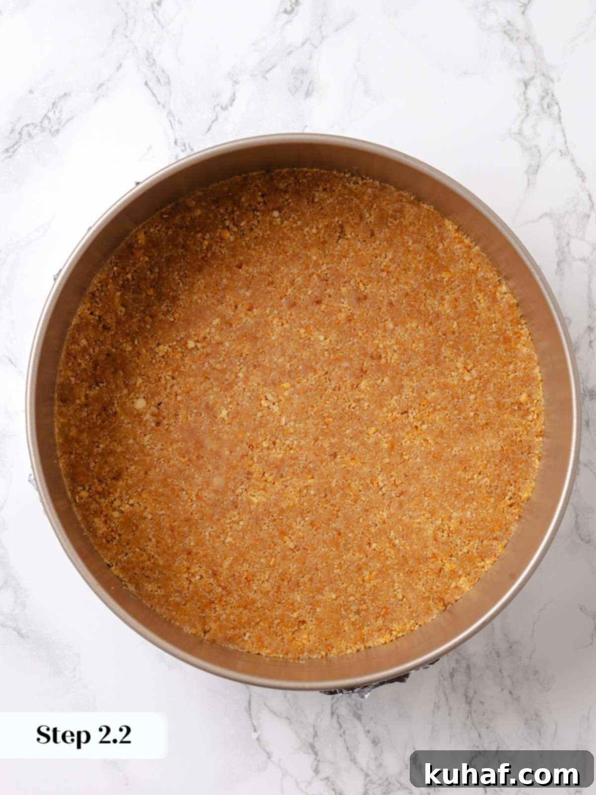 Graham cracker crust evenly pressed into a springform pan, ready for pre-baking.