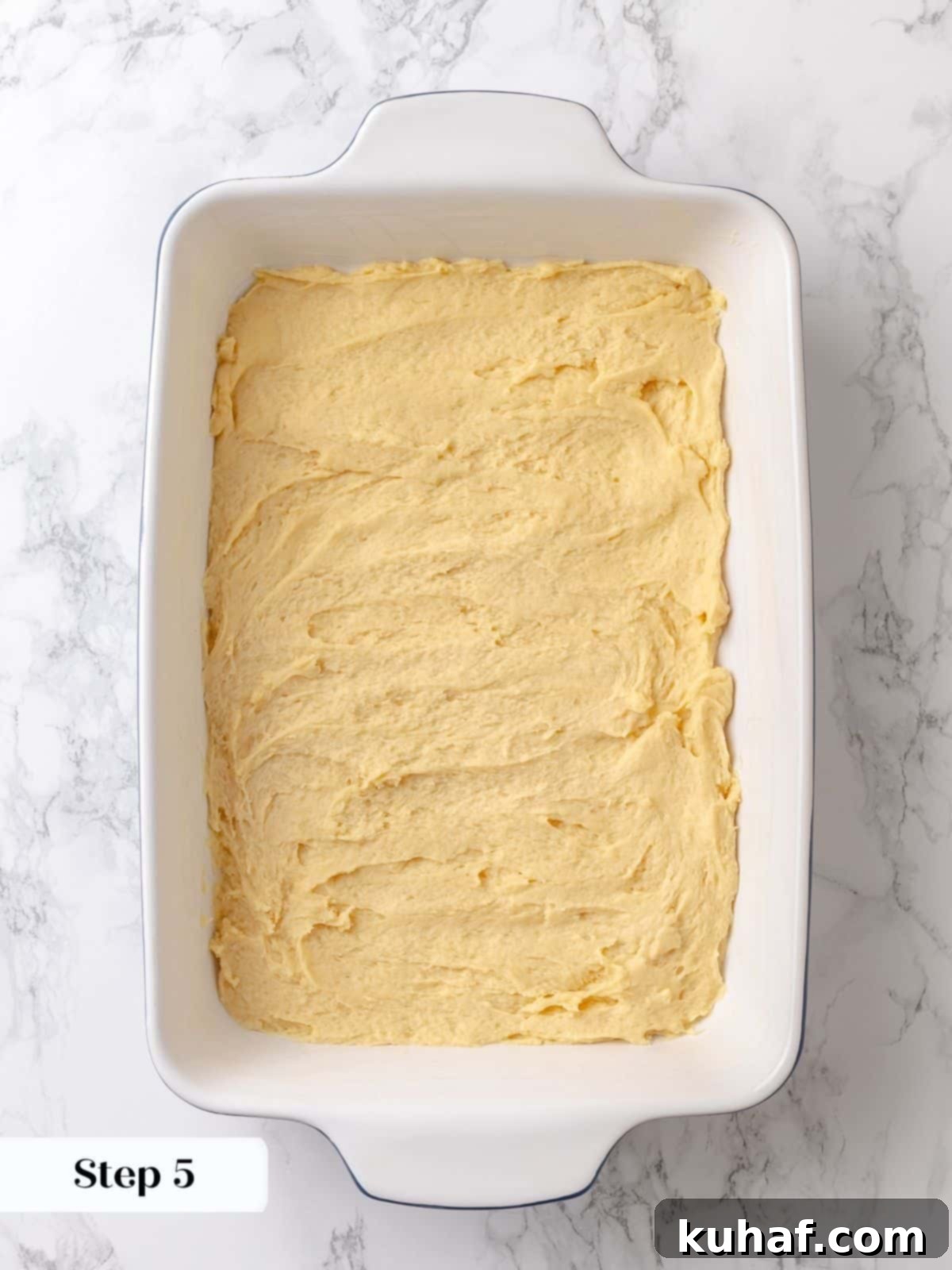 Cake dough is pressed into the dish with a spatula to create an even base.