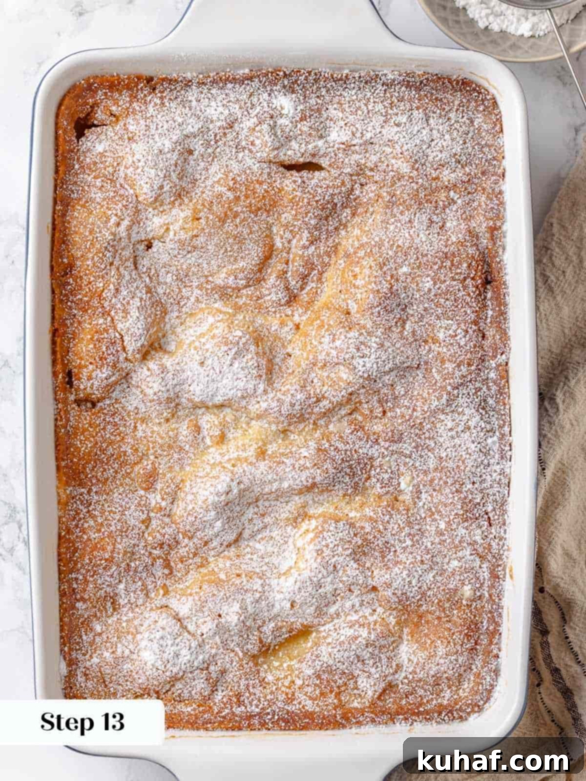 A thick layer of powdered sugar is dusted on top of the baked gooey butter cake.