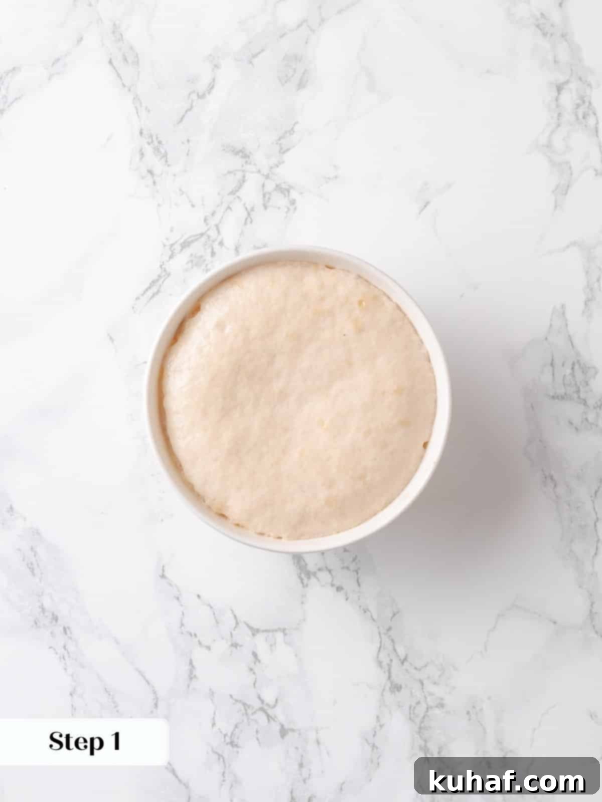 Yeast has foamed in warm water and milk, showing it's activated and ready.