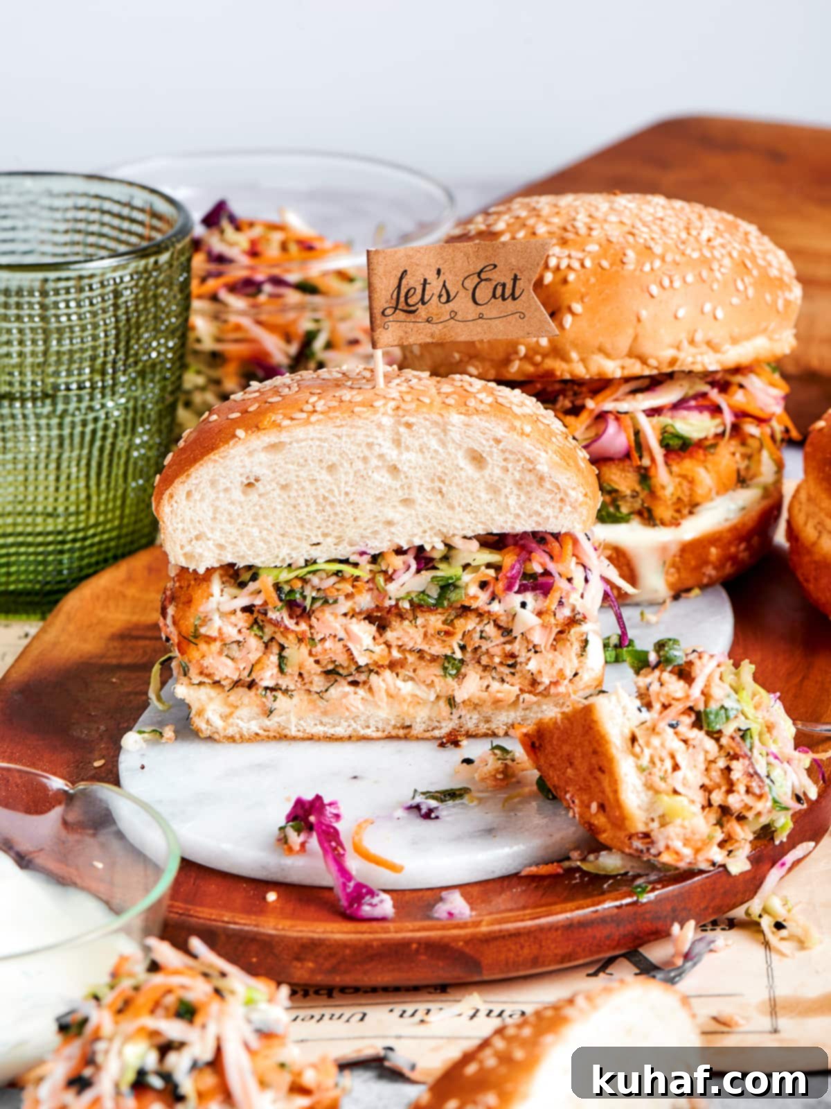 Hearty salmon burger with crisp slaw and sesame bun on a wooden serving dish.