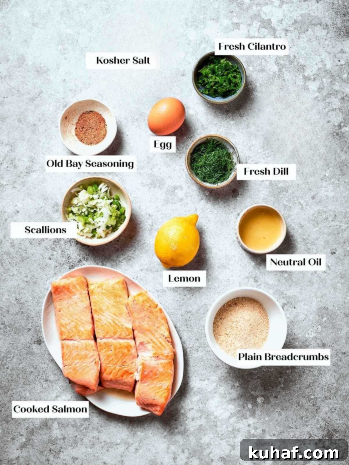 Prep station with ingredients like lemon, scallions, dill, and salmon for patty mixture.