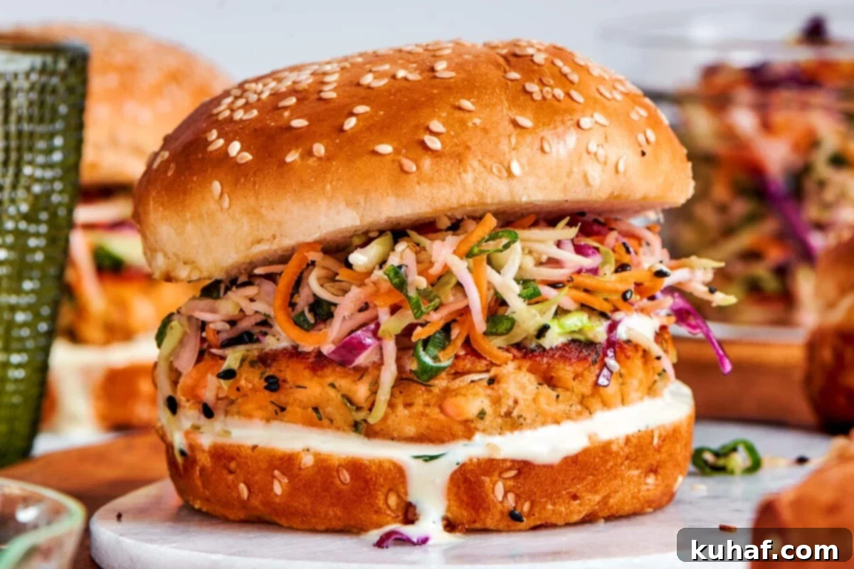 Fully assembled salmon burgers with slaw and sauce lined up and ready to eat.