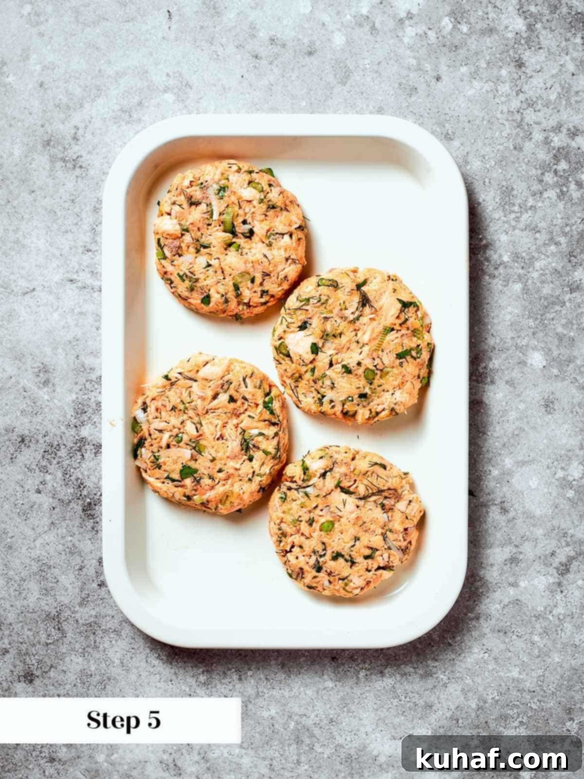 Formed salmon burger patties arranged on tray, prepped for chilling or cooking.