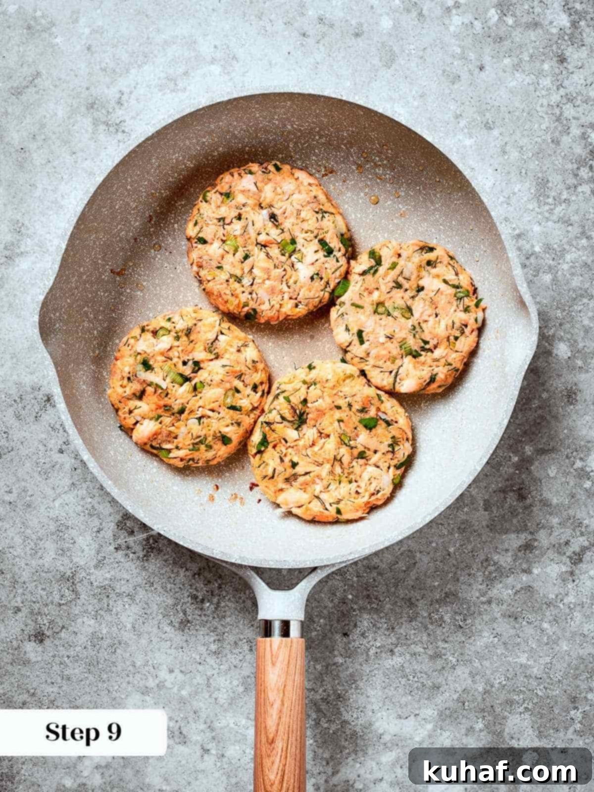 Salmon burger patties sizzling in a pan, developing golden brown crust.