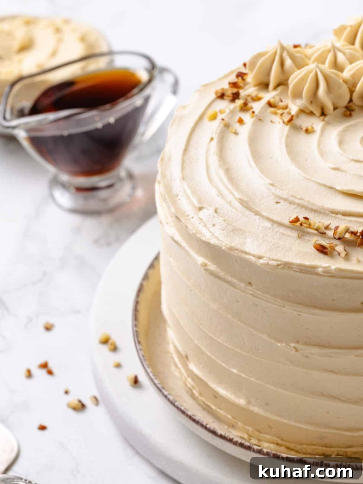 Golden Maple Frosting 2 A bowl of creamy maple frosting sits next to a bottle of maple syrup, highlighting the key ingredient for this rich recipe.