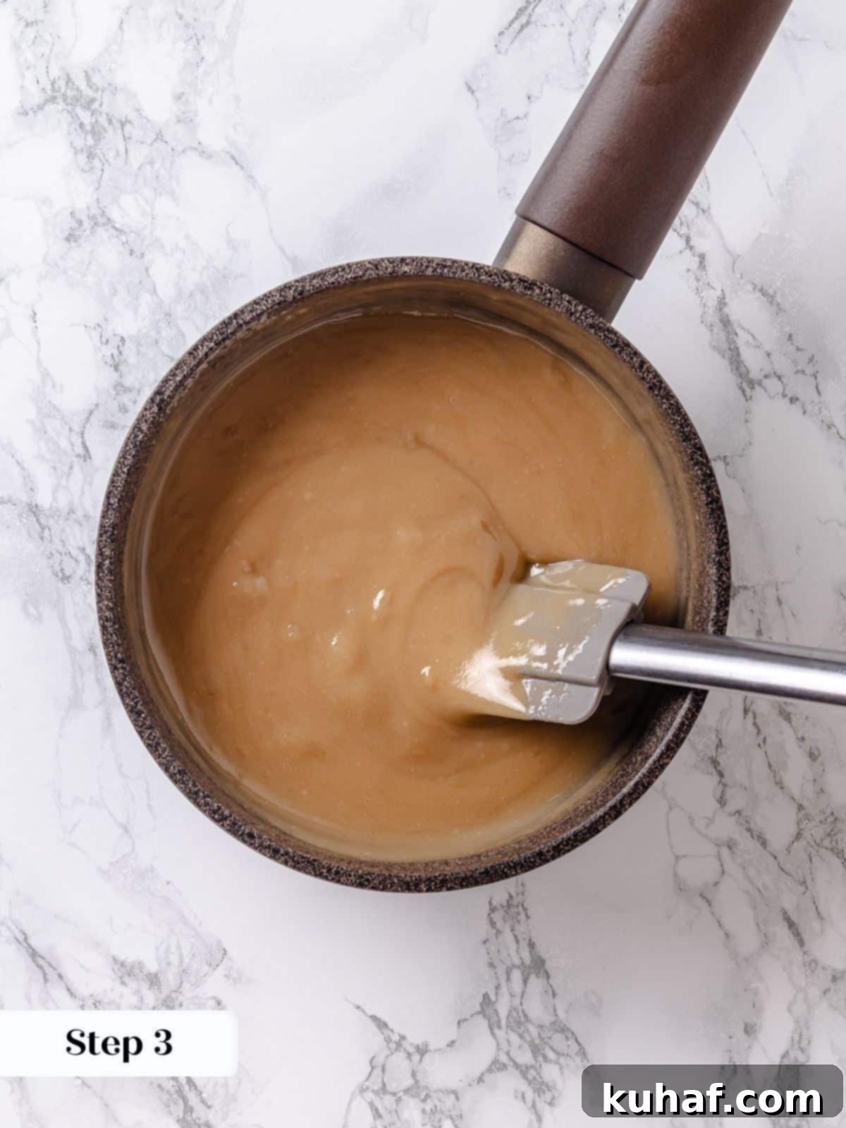 Golden Maple Frosting 8 A silicone spatula scrapes the thickened maple frosting base across the saucepan, ensuring even cooking and preventing burning.